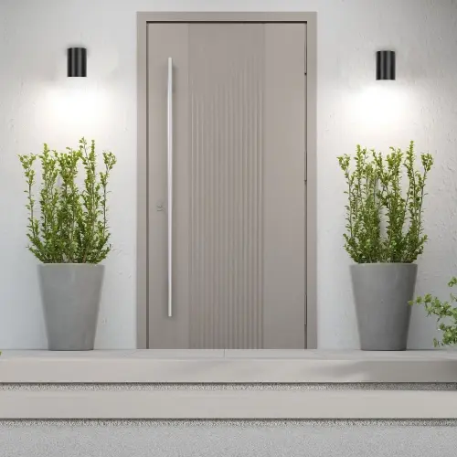 Lámparas solares colocadas a lo largo de un camino de jardín, modernas lámparas de pared exteriores junto a la puerta de entrada y una iluminación decorativa en forma de anillo al anochecer.